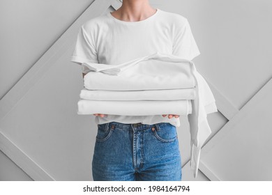 Woman With Stack Of Clean Bed Sheets On Light Background