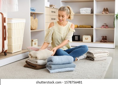 Woman With Stacks Of Clean Clothes At Home