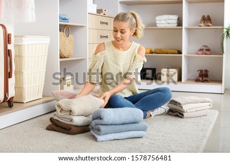 Woman with stacks of clean clothes at home