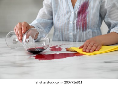 Woman with stain on her shirt cleaning spilled wine from white marble table indoors, closeup - Shutterstock ID 2007916811