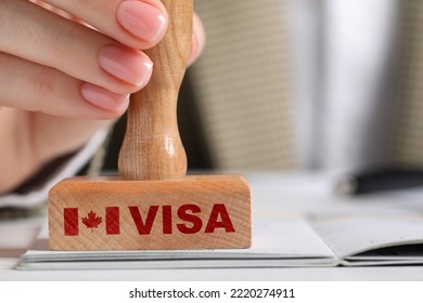 Woman stamping document at white wooden table, closeup. Visa for Canada - Shutterstock ID 2220274911