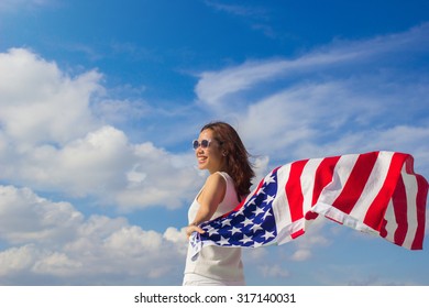woman stand facing the sky her hands holding America flag for freedom concept.