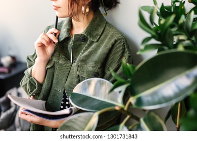 Woman Stand At Office Surround With Green Plants And Write At Her Note Book