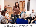 Woman Standing To Address Self Help Therapy Group Meeting In Community Center