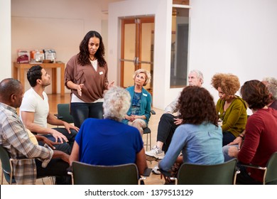 Woman Standing To Address Self Help Therapy Group Meeting In Community Center