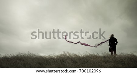 Woman standing alone in harsh weather with dramatic sky