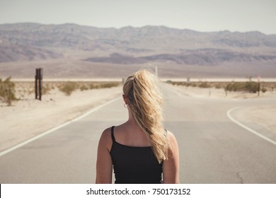 Woman Standing Alone On Street In The Middle Of Nowhere.