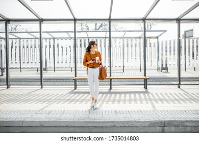 Woman standing alone at the public transport stop on a sunny day outdoors. Concept of a transportation and urban life - Powered by Shutterstock