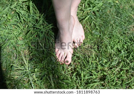 Woman standing barefoot in grass.