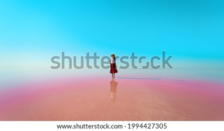 Woman standing in beautiful mirror reflection on blue sky on Sivash pink lake