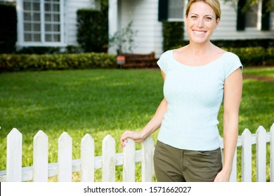 Woman Standing By The Garden Fence Outside Her New Home