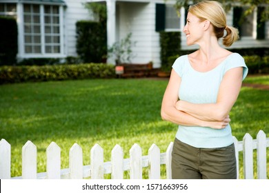 Woman Standing By The Garden Fence Outside Her New Home