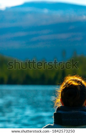 Woman standing by a mountain lake. Blurred background.