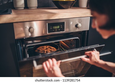 Woman standing by the oven and checking apple pie