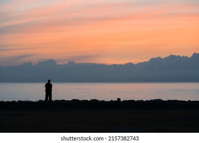 A Woman Standing By The Shore Watching Sunrise