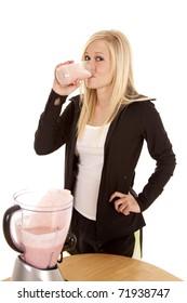 A Woman Is Standing By A Table Drinking A Smoothie