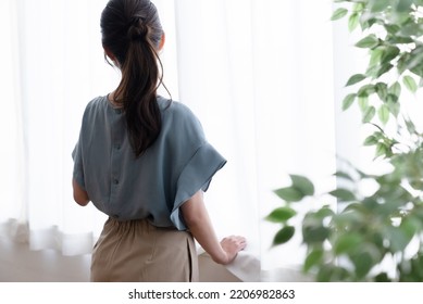 woman standing by the window - Shutterstock ID 2206982863