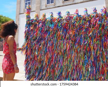A woman standing, and colorful Bonfim Ribbons attached to the front of the Church of the Miracle, Igreja de Nosso Senhor do Bonfim, Salvador, Brazil