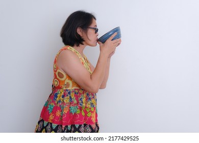 Woman Standing With Colorful Dress, Sipping Up A Bowl Of Soup