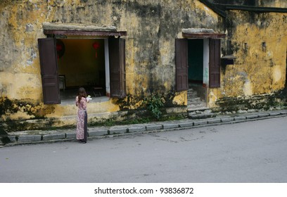 Woman standing in front of an ancient house, Hoi An Vietnam