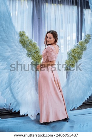 A woman standing in front of an angel wings backdrop