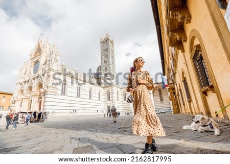 Woman standing in front of Siena cathedral. Traveling old towns of Tuscany region in Italy. Concept of visiting famous italian landmarks