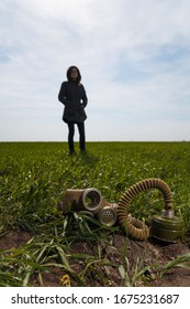 Woman Standing In Green Field On Clear Blue Sky Background And Gas Mask Lying In Grass On Foreground. Enviromental Protection, Ecology, Earth Saving, Pollution Prevention And Hope Concept. Copy Space.