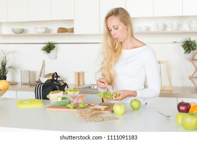 Woman Is Standing In Her Kitchen,holding Sandwich.Mom Preparing School Snack Or Lunch For Her Child In Home Kitchen.Homemade School Sandwiches.Packing In School Lunchbox.Lunch Box With Appetizing Food