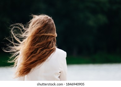 Woman standing looking at the lake. The hair was blown away by the wind. copy space. - Powered by Shutterstock