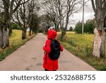 Woman standing in the middle of the road with red coat and backpack, thinking where to go and how to travel. Poland