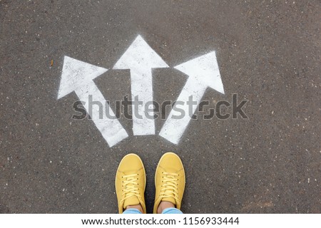 Woman standing near arrows on asphalt, top view. Choice concept