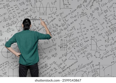 A woman is standing near a wall with a drawing of mathematical equations, graphs amd diagrams and pointing on it. Idea generating and thinking concept