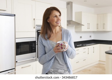 Woman Standing In New Luxury Fitted Kitchen