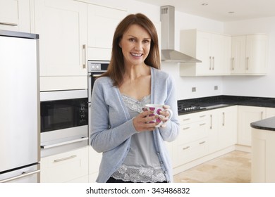 Woman Standing In New Luxury Fitted Kitchen