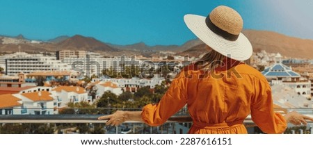 woman standing on balcony and enjoying view to the Playa de las Americas holiday resort skyline in Tenerife. banner with copy space