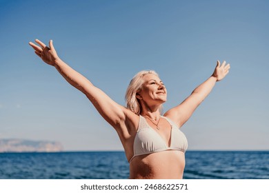 A woman is standing on the beach with her arms outstretched, smiling - Powered by Shutterstock