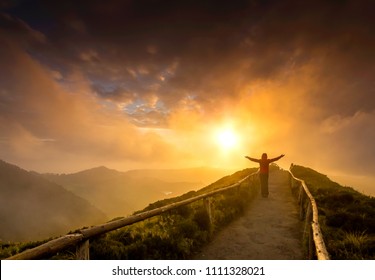 Woman standing on a beautiful path with arms open at the sunset - Shutterstock ID 1111328021