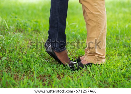 Woman standing on boyfriends toes in park