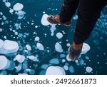 Woman standing on frozen methane bubbles at Abraham Lake, Alberta, Canada