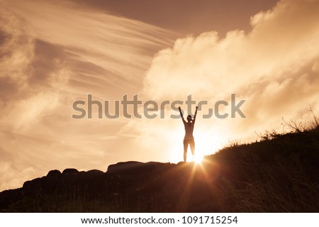 Woman standing on a mountain top with arms in the air celebrating. Victory and winning concept.
