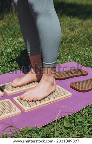 A woman is standing on a sadhu board. Close-up of legs .yoga nails in nature.