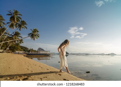 Woman Standing On The Sand In The El Nido Beach, Tasting The Temperature Of The Water Dipping Her Toe While On A Summer Holiday. Travel And Outdoors Lifestyle.