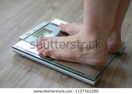 Woman standing on a scale in the bathroom for controlling the diet