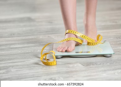 Woman Standing On Scales On Wooden Floor. Concept Of Weight Loss