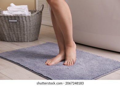 Woman standing on soft grey bath mat near tub at home, closeup