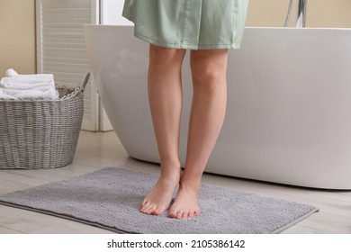 Woman standing on soft grey bath mat near tub at home, closeup