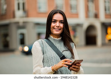 Woman standing on street and using mobile. Focus is on woman.  - Shutterstock ID 1948141528