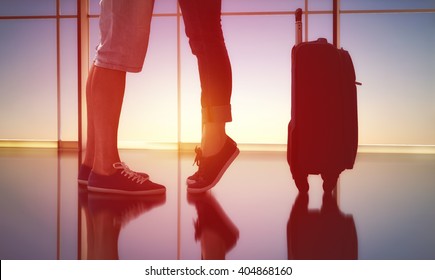 Woman Standing On Tiptoe Beside Her Man. The Embrace Of Men And Women In The Airport. The Concept Of Farewells And Meetings.