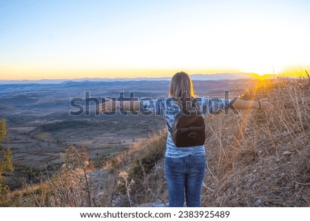 Woman standing on top of mountain and looking at view during sunset
