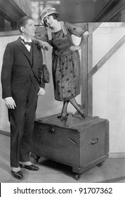 Woman Standing On A Trunk Next To A Very Tall Man